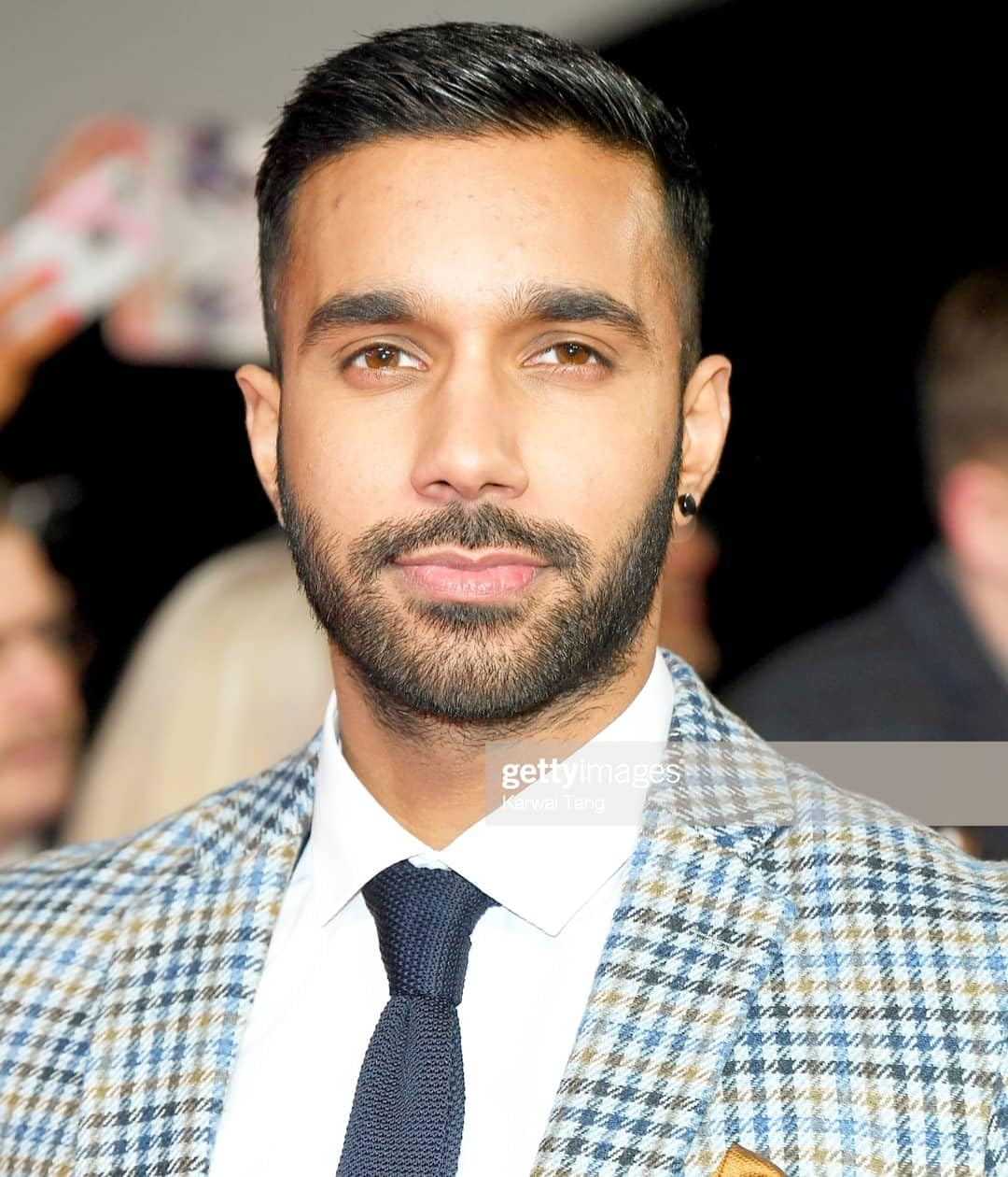 a man in a suit and tie looking at the camera with other people behind him - Rishi Nair’s Height: Breaking Down the Record-Setter